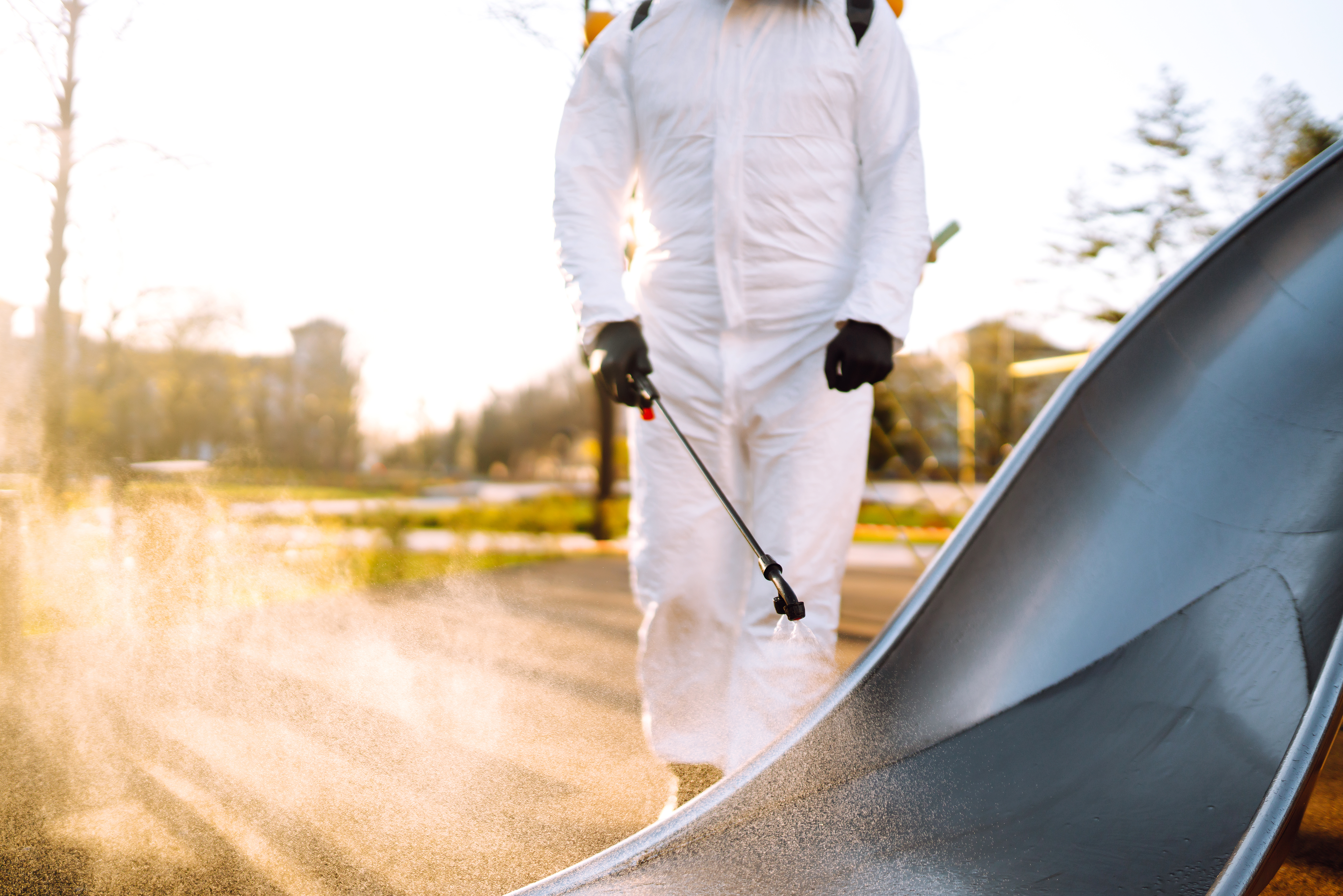 Technicien en combinaison désinfectant une aire de jeux par pulvérisation